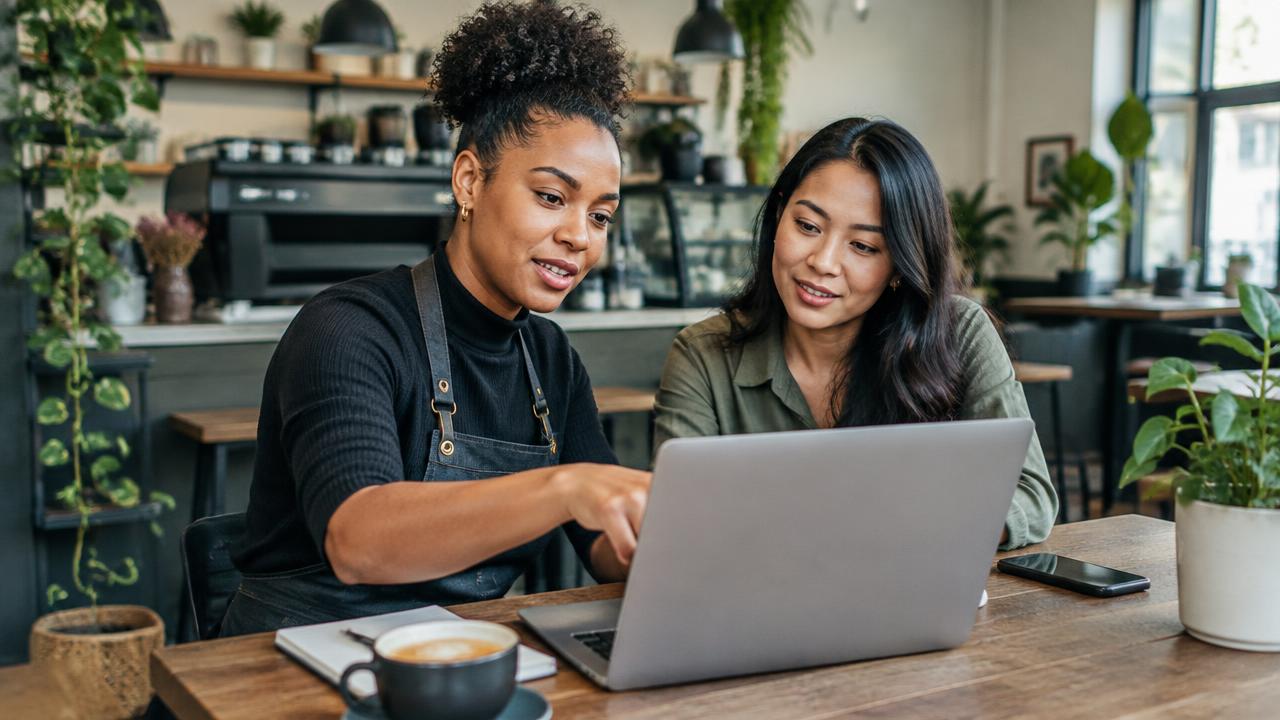 Two cafe owners planning small business growth together on a laptop